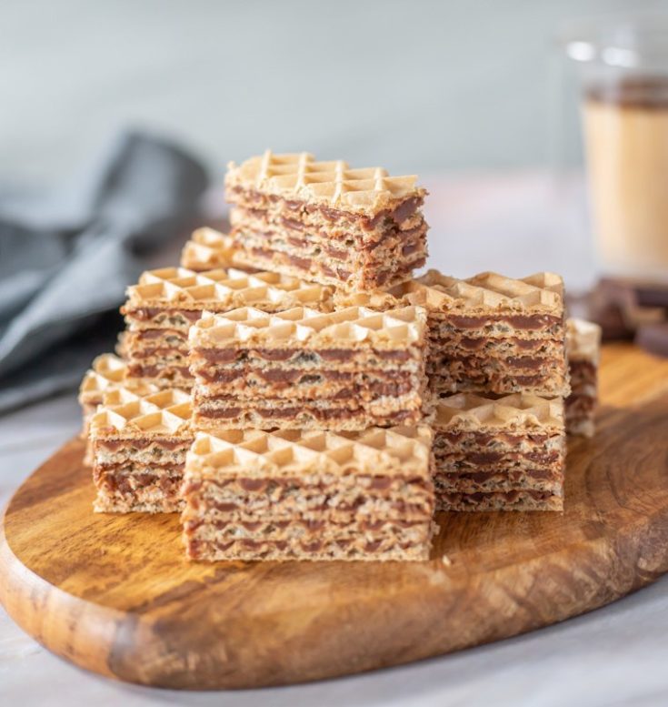 A stack of waffles with a cup of coffee.