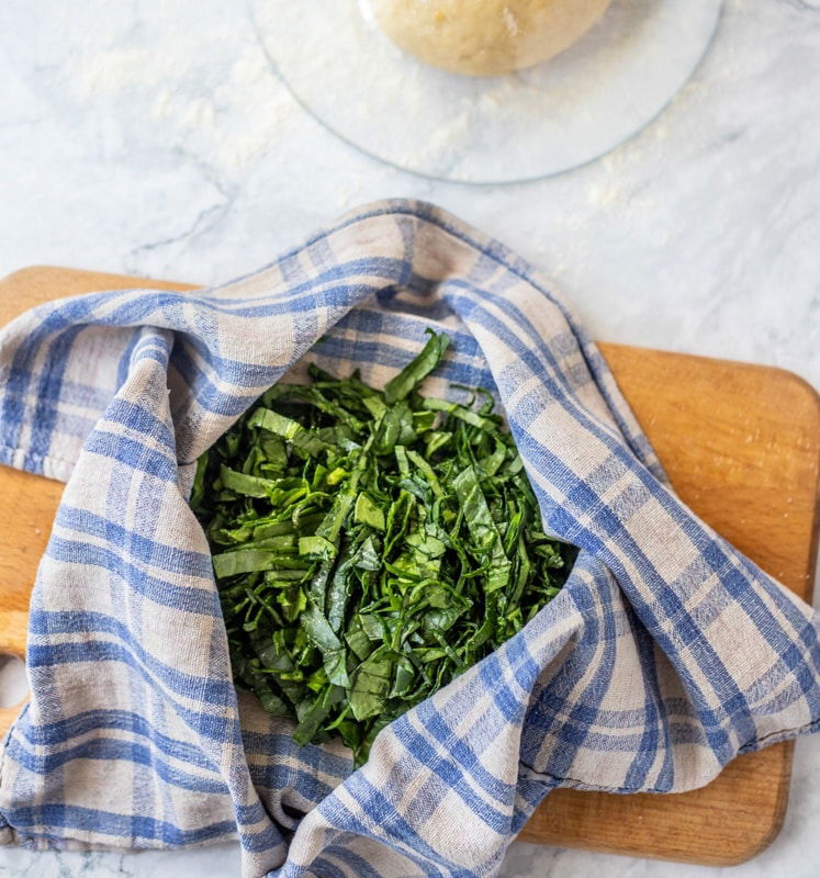 Croatian greens on a cutting board next to a rolling pin, perfect for Rudarska Greblica recipe.