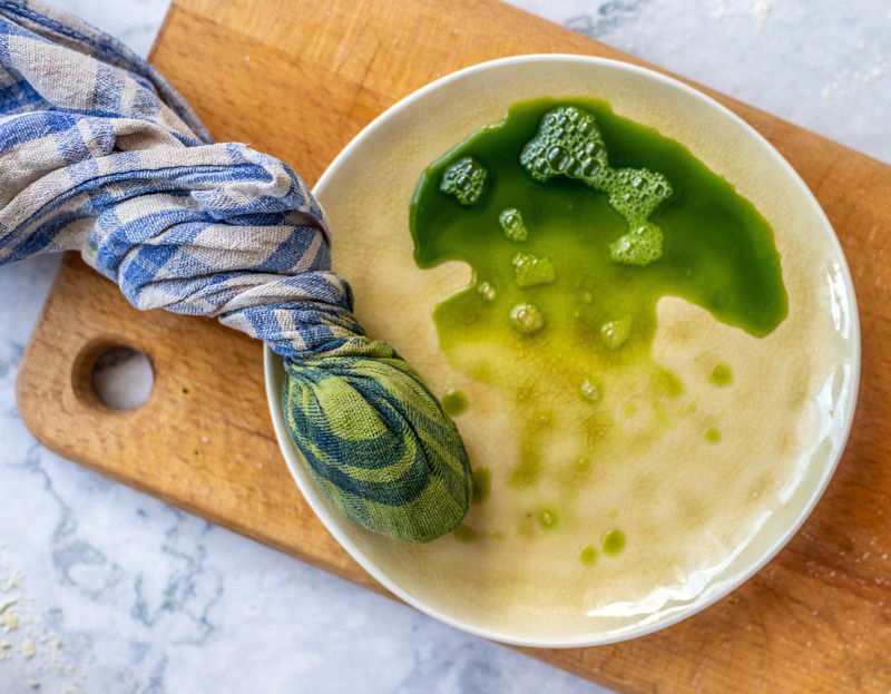 A bowl of Rudarska Greblica soup, a traditional Croatian recipe, with green liquid on top.