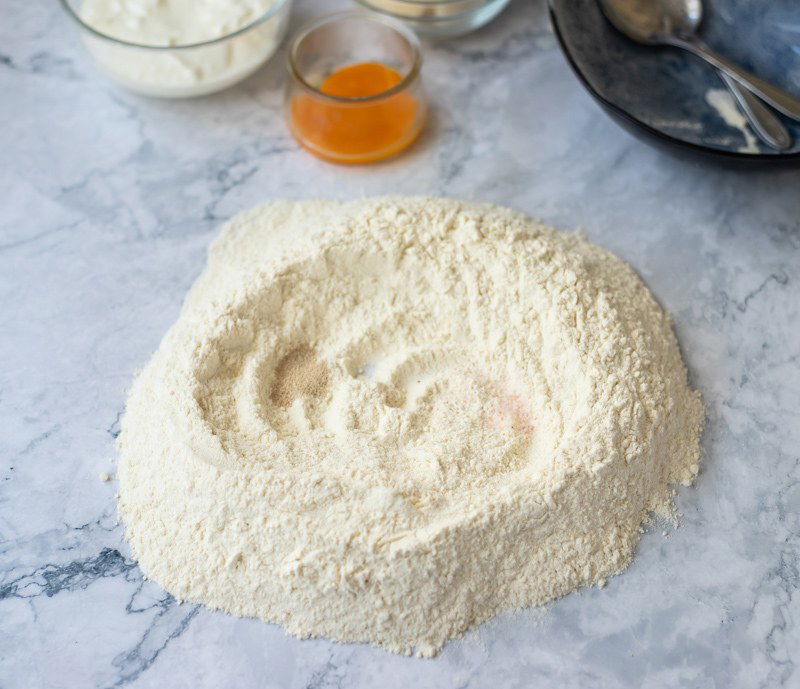 A bowl of flour and other ingredients on a marble table, ready to create a delicious Rudarska Greblica, a traditional Croatian recipe.