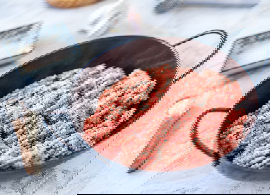 Sarajevski Ćevapi sizzling in a pan on a marble table.