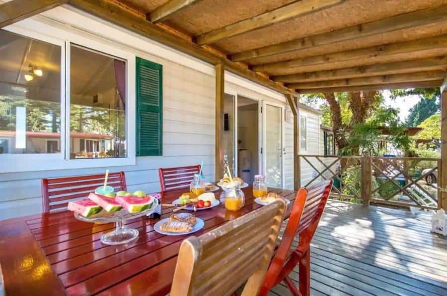 A wooden deck in Croatia with a table and chairs on it, perfect for glamping.