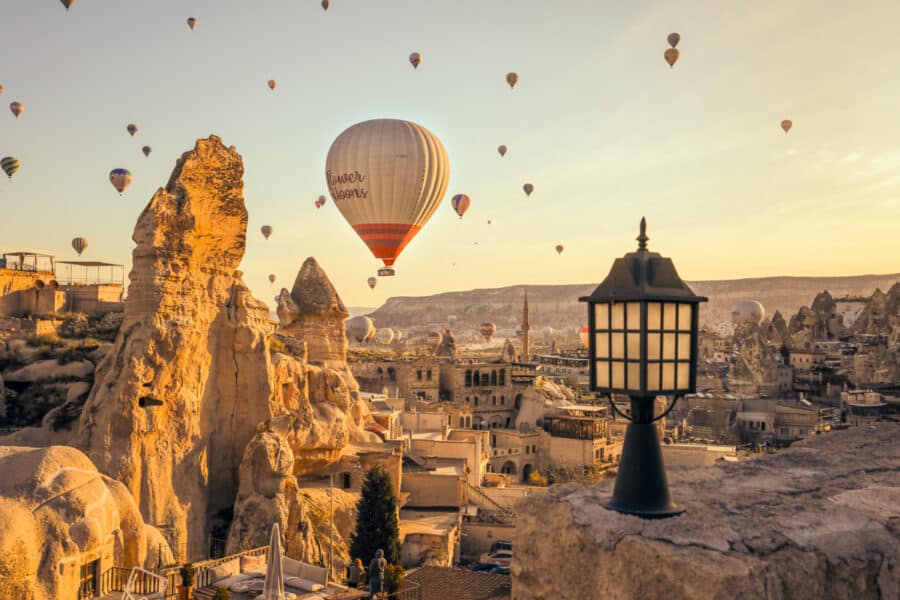 Hot air balloons floating over Cappadocia's rocky landscape at sunrise, with a lantern in the foreground, illustrating how to spend 3 days in Cappadocia.