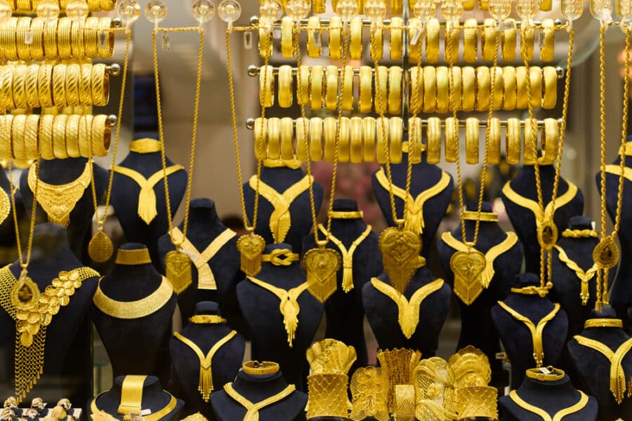 A captivating display of various gold jewelry pieces, including necklaces, bracelets, and rings, adorns black mannequin stands in the shop window, evoking the opulence of the Istanbul Grand Bazaar.